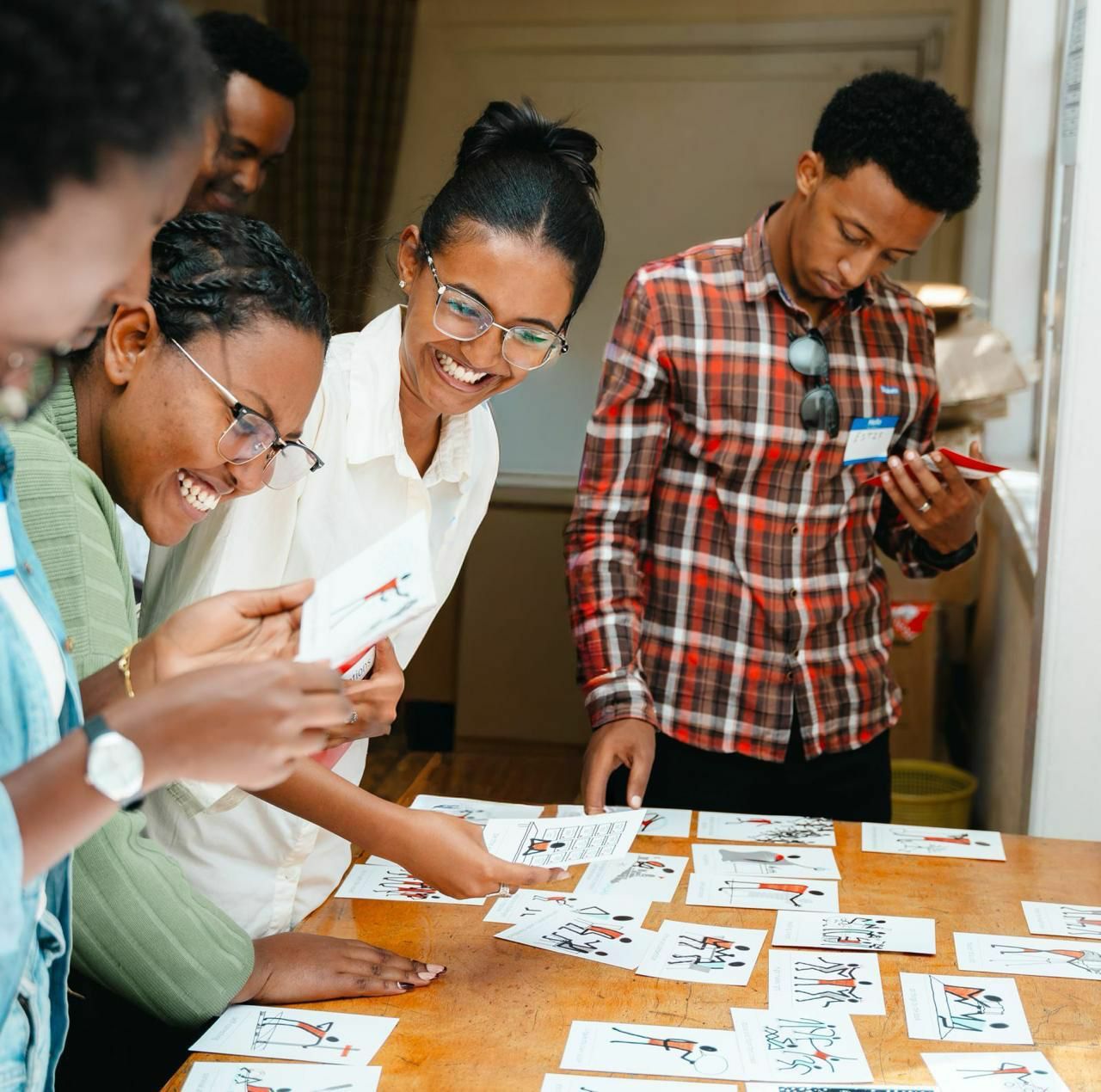 Young leaders laughing together as they sort cards at a table during a training session